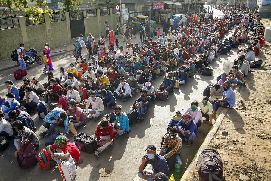 Migrants wait for a means of transport to reach a railway station and board a special train to their native place in Uttar Pradesh. PTI