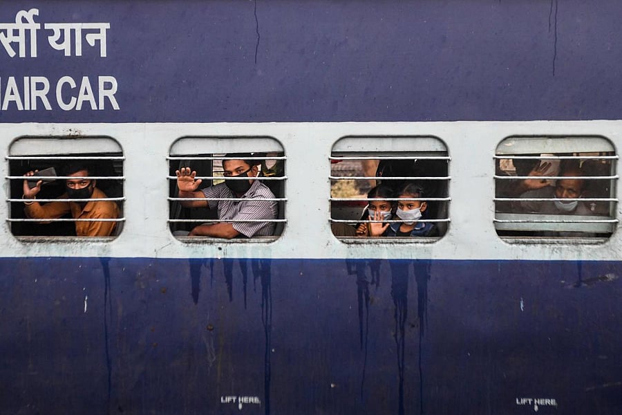 Migrant workers and families wave from the windows of a special train (AFP Photo)