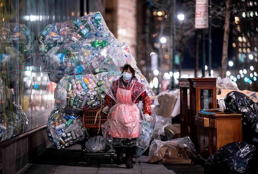 A woman wearing a face mask and a plastic bag pulls a cart loaded with bags of recyclables through the streets of Lower Manhattan during the outbreak of the novel coronavirus. (AFP Photo)