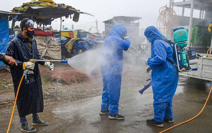 Employees of the Srinagar Municipal Corporation (SMC) spray disinfectant to each other after sanitizing a police station (PTI Photo)