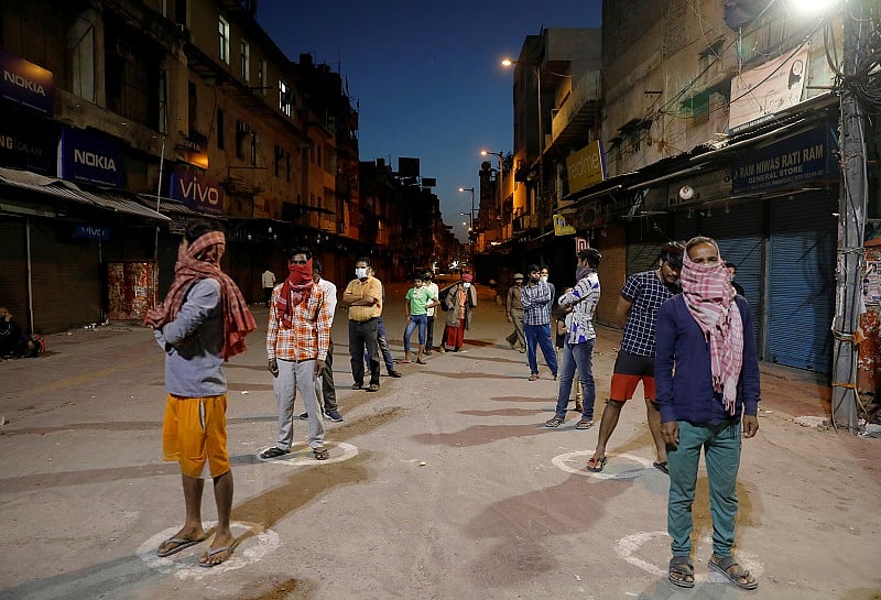 People stand apart in a line to receive free food being distributed on a street during a 21-day nationwide lockdown to limit the spreading of coronavirus disease. (Reuters Photo)