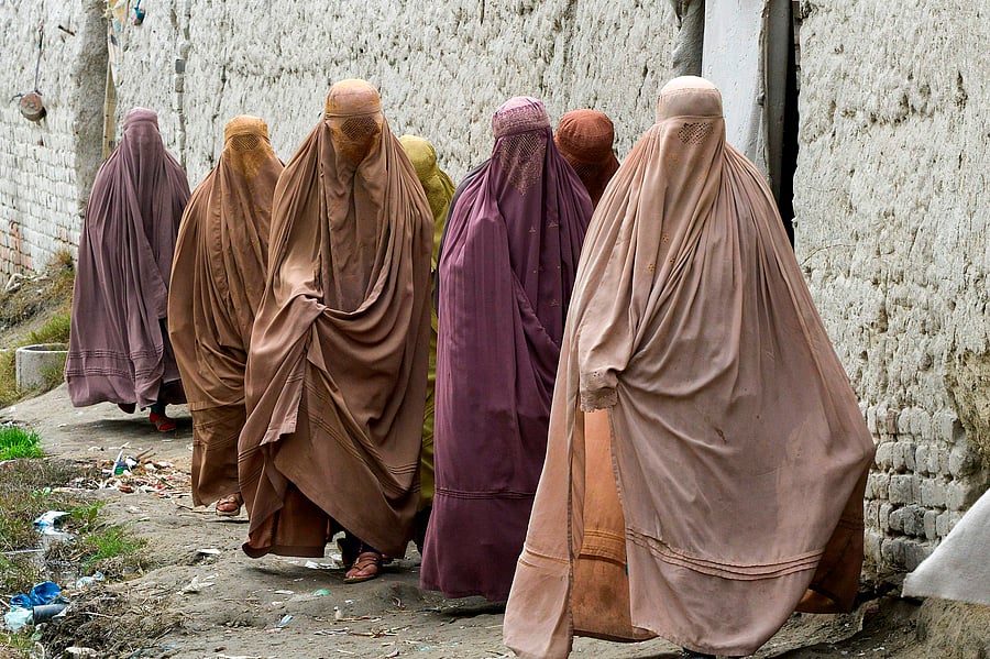 In this picture taken on February 12, 2020, Afghan refugee women walk in a refugee camp in Peshawar. (Credit: AFP Photo)
