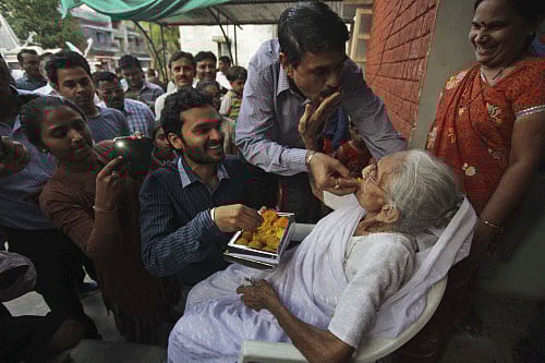 Relatives offer sweets to Hiraben, mother of Narendra Modi,as they celebrate Modi's swearing-in ceremony. AP photo