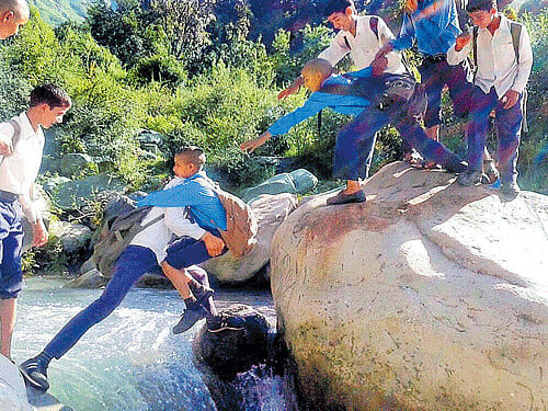 leap of faith: Students take risk to cross a river in the absence of a bridge at Badhul area of Rajouri on Tuesday. PTI