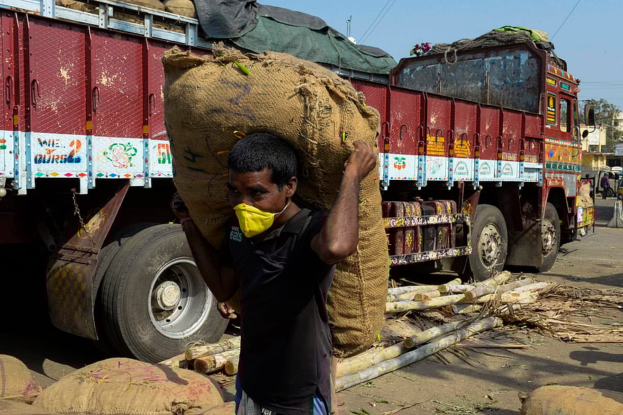 A labourer wears a facemasks carries a sack of green chillies at a wholesale market following Telangana's State government order for a complete lockdown. (Credit: AFP)