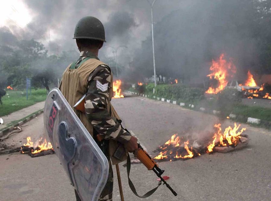 A Security personnel stands towards vehicles burning in violence following Dera Sacha Sauda chief Gurmeet Ram Rahim's conviction in Panchkula on Friday. PTI Photo