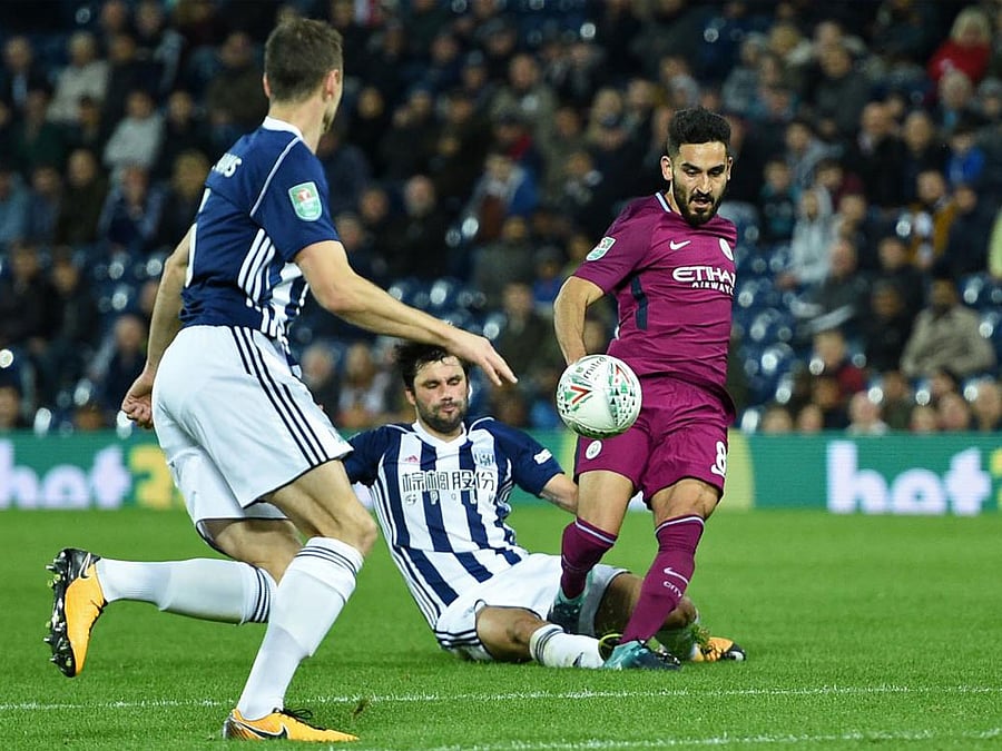 West Bromwich Albion's Argentinian midfielder Claudio Yacob (C) is booked for this tackle on Manchester City's German midfielder Ilkay Gundogan (R) during the English League Cup third round football match between West Bromwich Albion and Manchester City at The Hawthorns in West Bromwich, central England. AFP PHOTO