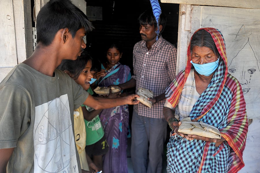 A man staying near a tech park in Bengaluru gives food packets to his family as the workers struggle to make ends meet due to the COVID-19 lockdown in the city. (DH Photo)