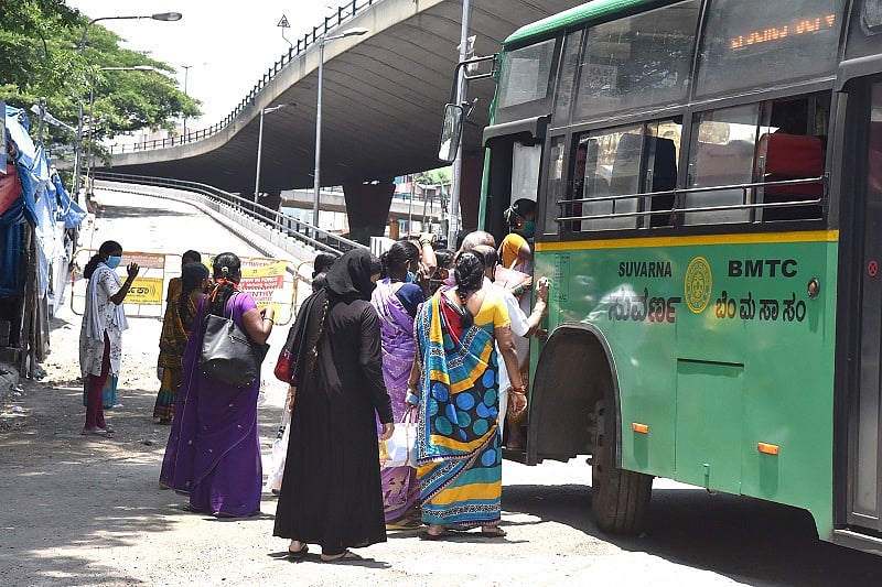 Essential service people rush to climb the essential service BMTC bus to reach their destinations, due to COVID-19 lockdown. (DH Photo)