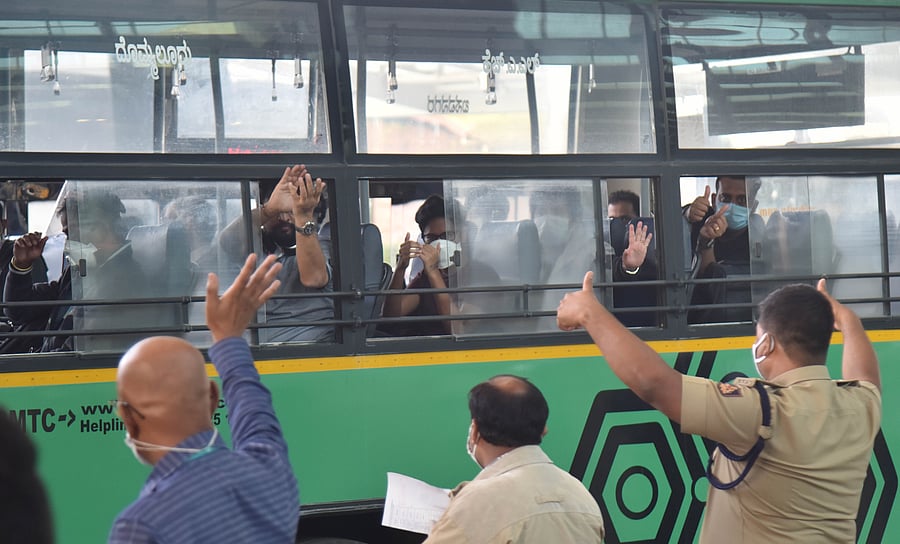 Passengers from the flight, Air India (AI 1803) coming from London, before leaving 14 days quarantine waves from bus to Corona warriors at Kempegowda International Airport. (DH Photo)