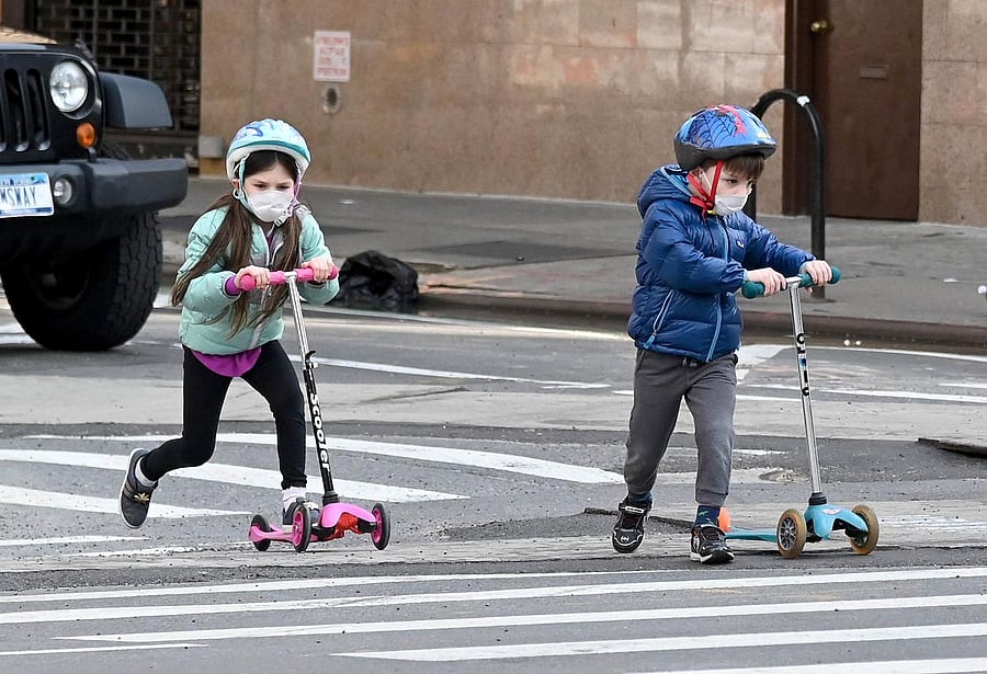 Children wearing face masks play on their scooters during the coronavirus pandemic on April 25, 2020 in New York City. Credit: AFP Photo
