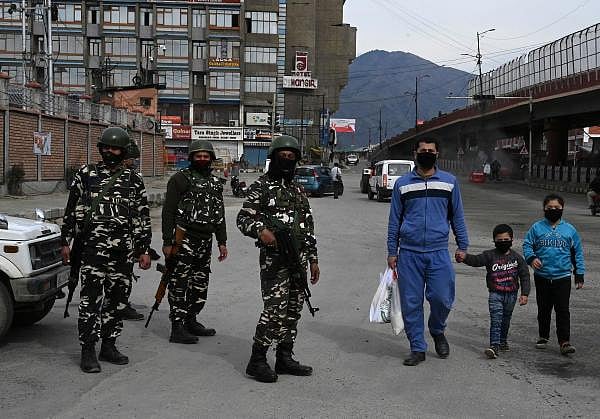 A family wearing facemasks walk along a street during a government-imposed nationwide lockdown as a preventive measures against the COVID-19 coronavirus, in Srinagar on April 3, 2020. (Credit: AFP Photo)