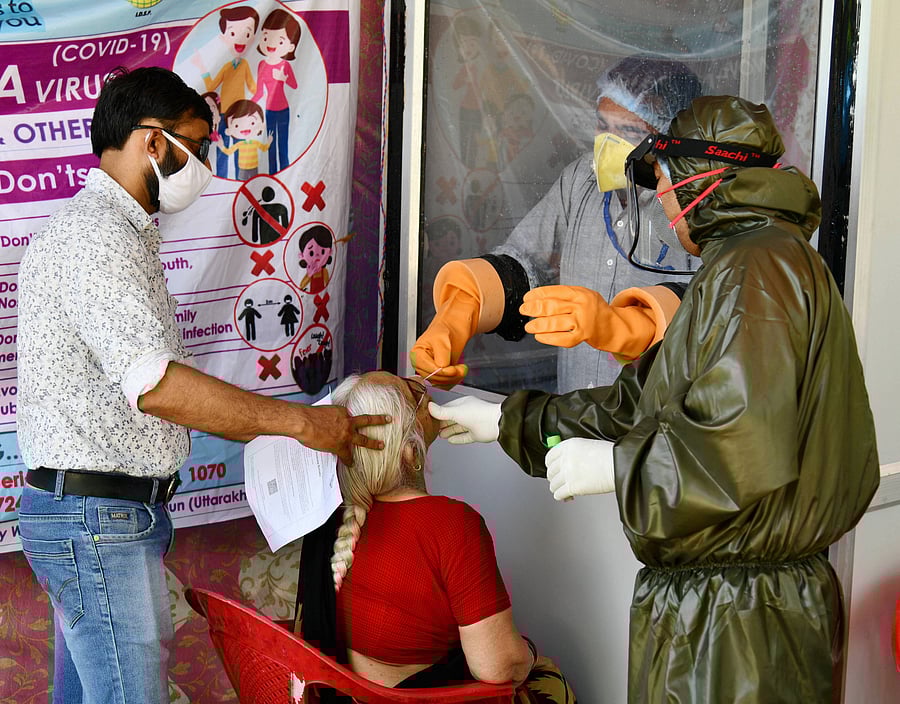 Medics take a swab sample of an elderly-woman for COVID-19 testing at Asha Rodi police check post, during the ongoing nationwide lockdown, in Dehradun, Friday, May 15, 2020. (PTI Photo)