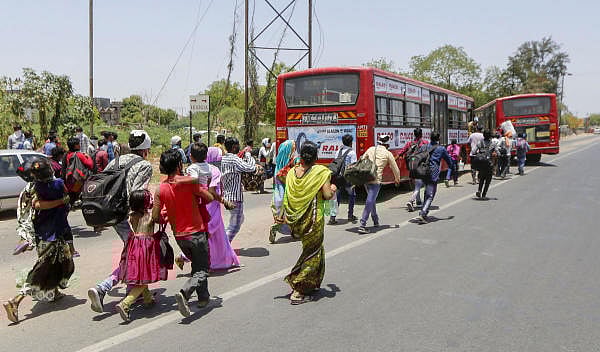 Migrant workers run to catch a bus for the railway station to return to their homes in UP and Bihar, amid ongoing COVID-19 lockdown in Ahmedabad, Friday, May 8, 2020. (PTI Photo)