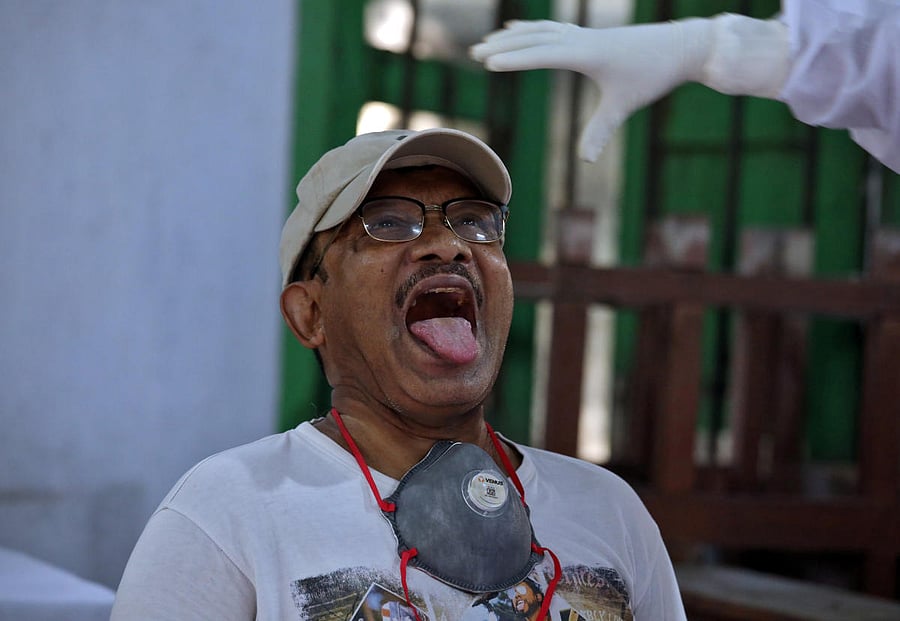 A man reacts as a medic wearing protective gear prepares to take a swab from him to test for the coronavirus disease in Kolkata. (Reuters photo)