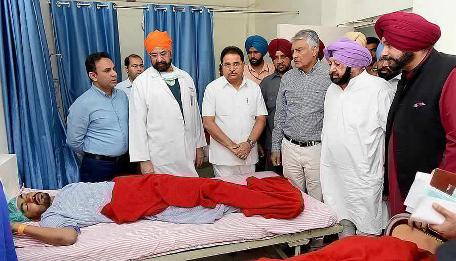 Punjab Chief Minister Capt Amarinder Singh with Punjab Minister Navjot Singh Sidhu visit a victim of the train accident at Jodh Phatak, at Civil Hospital in Amritsar on Saturday. PTI photo
