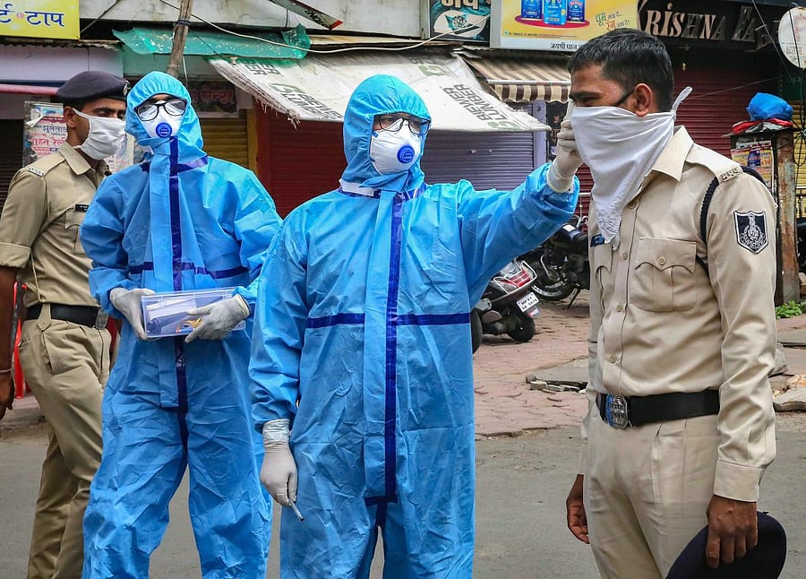 Thermal screening of security personnel being conducted as they stand guard on a street during a nationwide lockdown in the wake of coronavirus pandemic, in Bhopal. Credit: PTI Photo