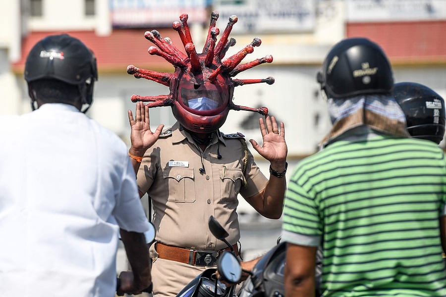 Police inspector Rajeesh Babu wearing a coronavirus-themed helmet speaks to motorists at a checkpoint in Chennai. Credit: AFP Photo/Arun Sankar