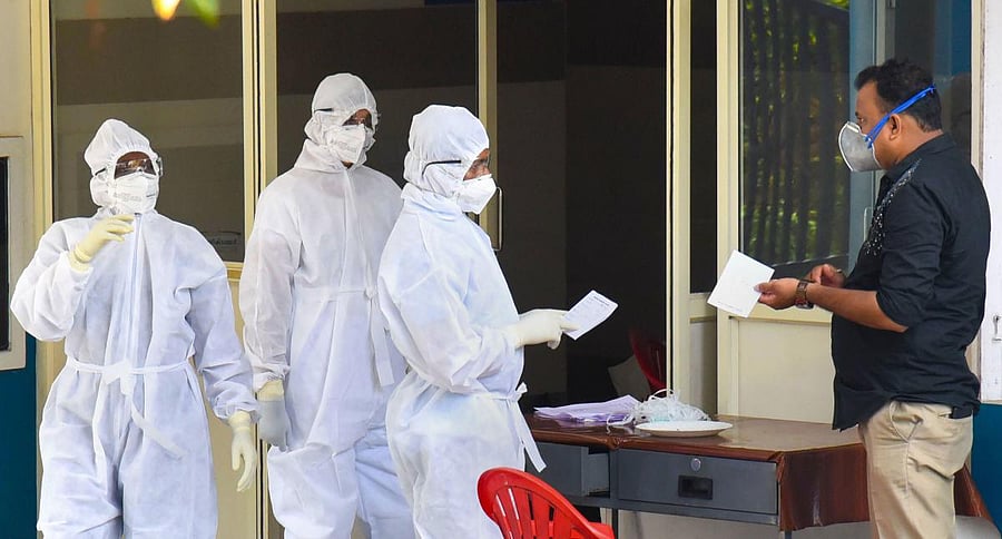 Medical staff members wear masks and protective suits to mitigate the spread of coronavirus, outside the special isolation ward of District Hospital Aluva in Kochi. (PTI Photo)
