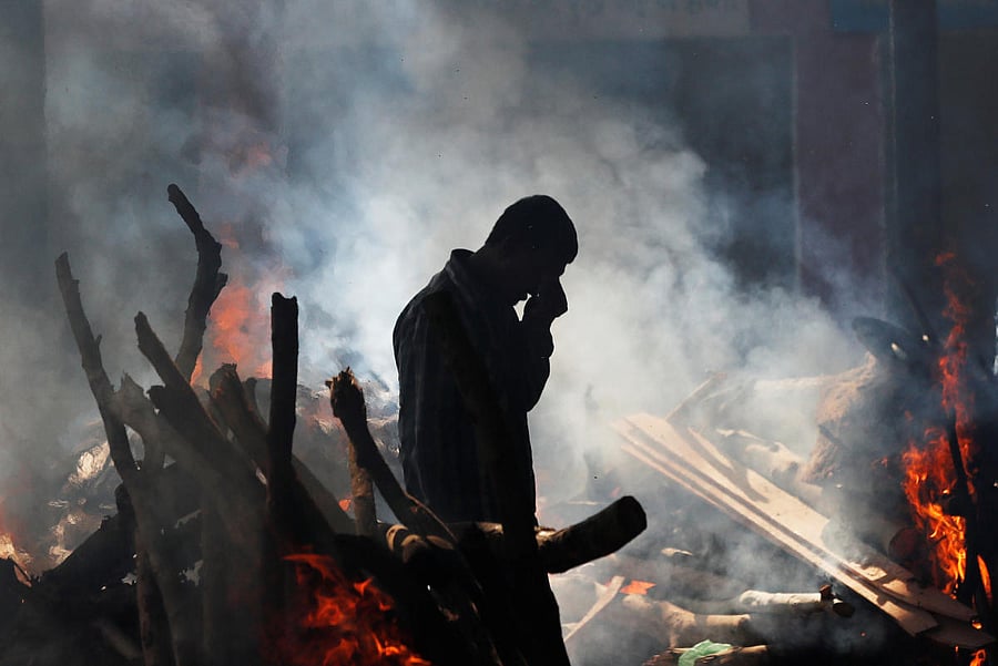 A man cries as he stands next to the burning pyre of a family member who died after a train traveling at high speed ran through a crowd of people on the rail tracks on Friday, at a cremation ground in Amritsar on Saturday. REUTERS