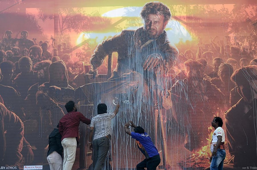 Fans spray milk on a billboard displaying the picture of Bollywood star Rajinikanth before attending the show of the new Tamil-language film 'Pettai' in Chennai on Thursday. AFP