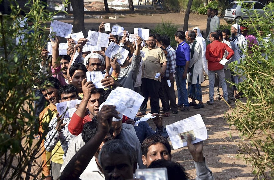 Voters show their identity cards as they stand in a queue at a polling station to cast vote during the second phase of the general elections, in Mathura, Thursday, April 18, 2019. (PTI Photo)