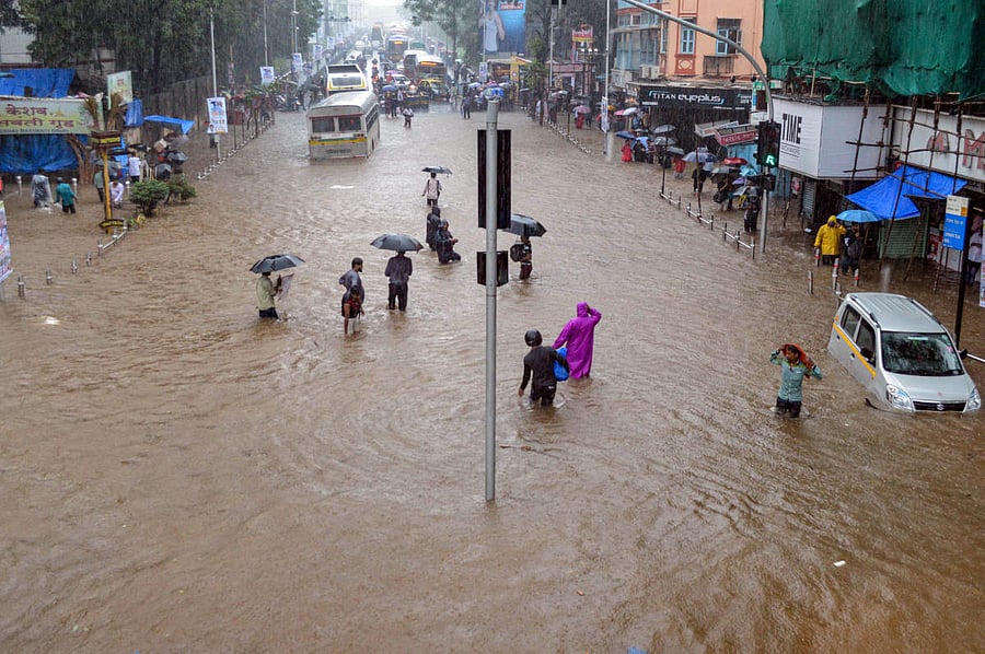 Residents wade through a flooded street, following heavy rains in the low lying area of Dadar, in Mumbai. PTI File Photo