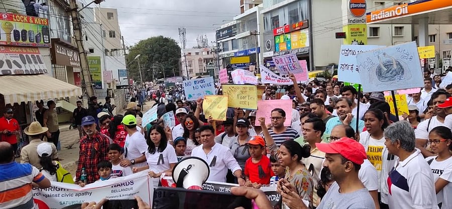 Citizens take out a march along Haralur Main Road in protest against poor infrastructure on Saturday. SPECIAL ARRANGEMENT