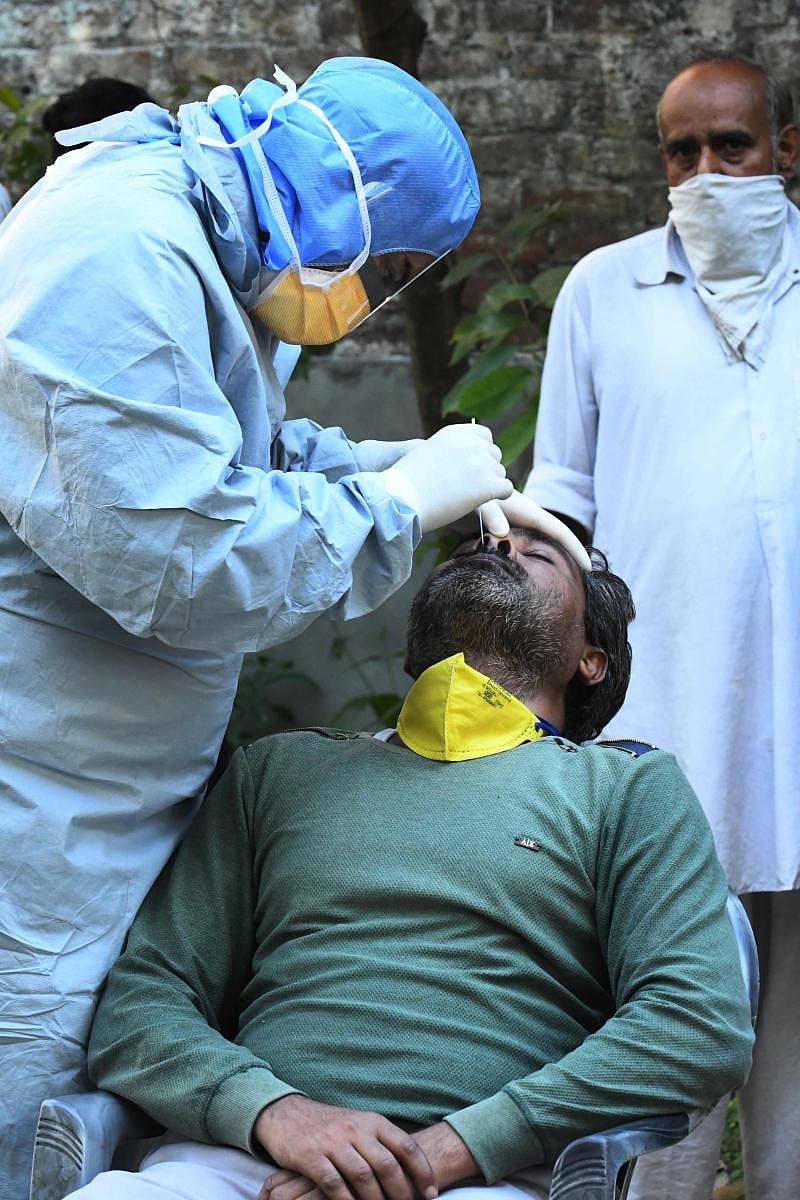 A doctor takes a sample from man for a RT-PCR COVID-19 test during a government-imposed nationwide lockdown as a preventive measure against the COVID-19 coronavirus, in Amritsar on April 23, 2020. (Photo by NARINDER NANU / AFP)