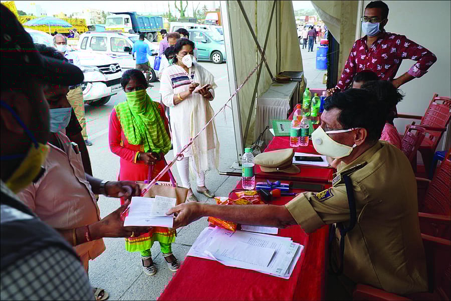 A police inspector examines travel documents of people seeking to enter Karnataka at Attibele. DH PHOTO/Akhil Kadidal
