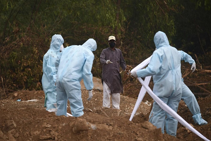Gravedigger Mohammed Shamim (L) instructs relatives of a COVID-19 coronavirus victim during the burial at a graveyard in New Delhi. (AFP Photo)