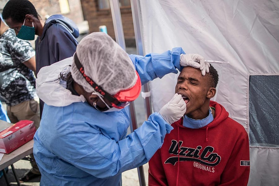 Doctors Without Border (MSF) nurse Bhelekazi Mdlalose (C) performs a COVID-19 coronavirus test during a Ministry of Health screening and testing drive in the Wolhuter men's hostel in Jeppestown district of Johannesburg, on May 14, 2020. Credit: AFP Photo