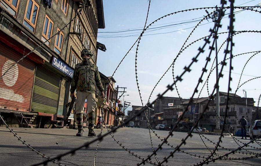 Security personnel guard at a closed road during restrictions in Srinagar. (PTI Photo)