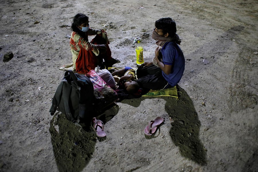 Migrant workers wearing protective face masks wait to cross the border to their home state of Uttar Pradesh, during an extended nationwide lockdown to slow the spread of the coronavirus disease (COVID-19), in New Delhi, India. Credit: Reuters Photo