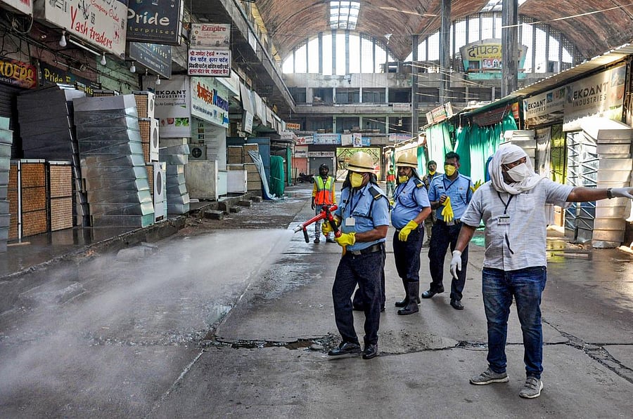 Firefighters spray disinfectants outside closed shops at a market to contain the spread of coronavirus in Nagpur. (PTI Photo)