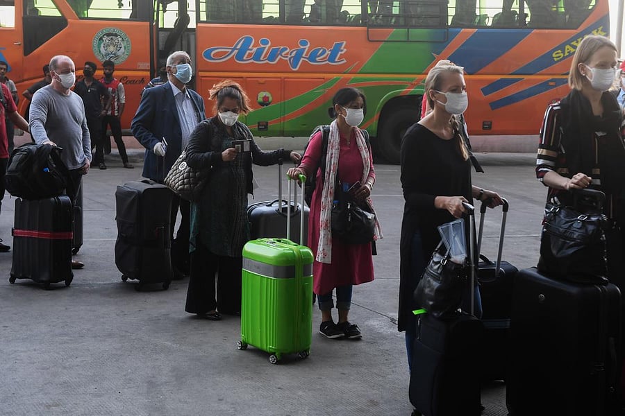 Foreign nationals wearing facemasks line up to board a special evacuation flight during a government-imposed nationwide COVID-19  lockdown (AFP Photo)