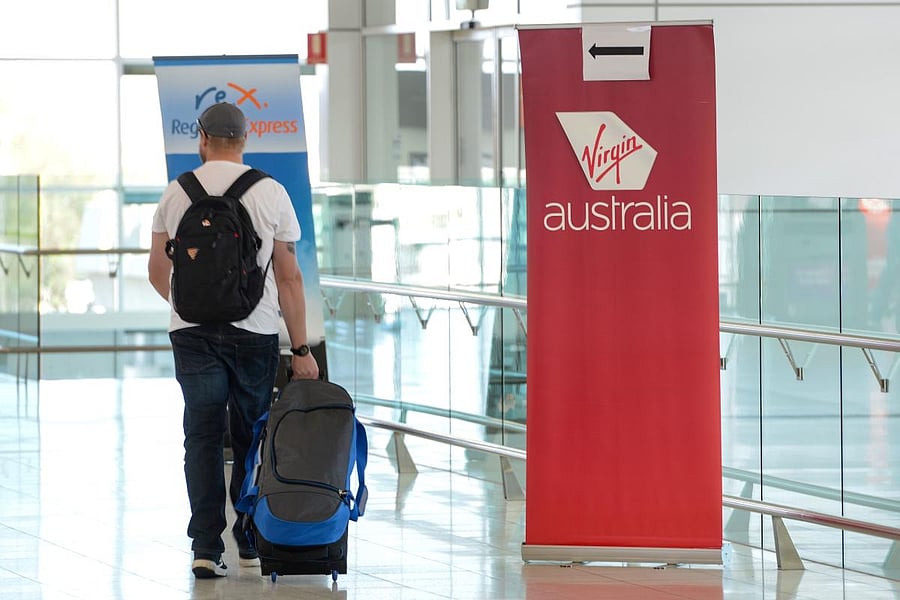 A traveller walks past a sign for Virgin Australia in the departures area at Adelaide Airport in Adelaide on April 21, 2020. Credit: AFP Photo