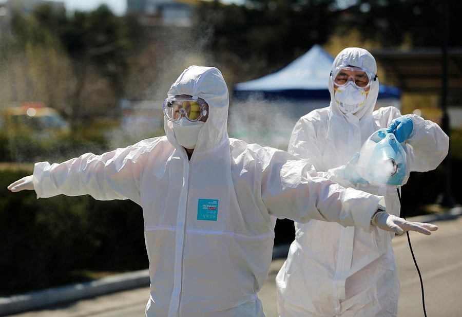 A quarantine worker sprays disinfectants on an ambulance worker of the 119 rescue team, who went on his duty amid the rise in confirmed cases of coronavirus disease (COVID-19) in Daegu, South Korea, March 14, 2020. (Reuters Photo)