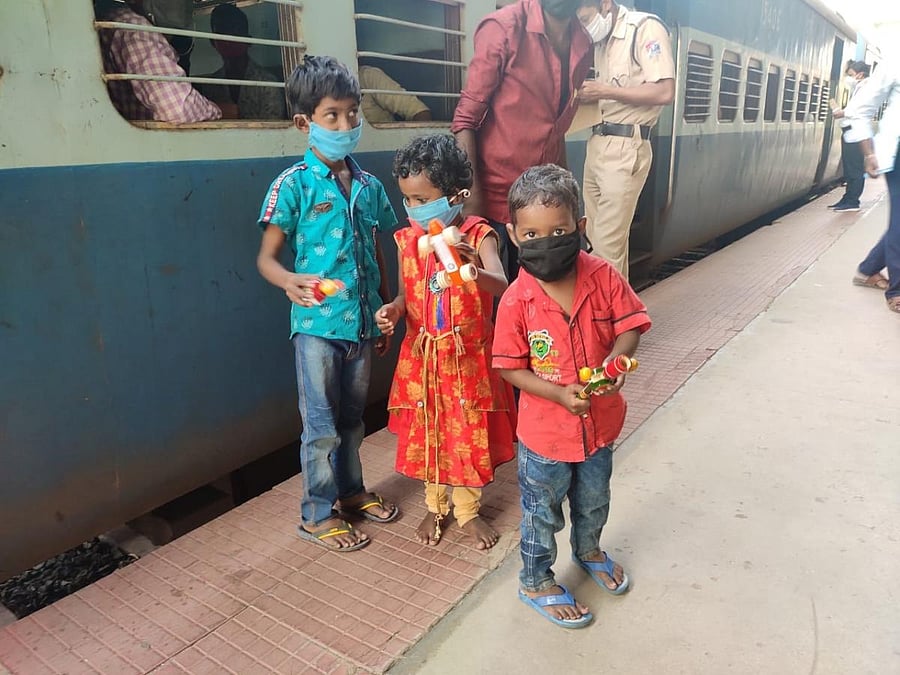 Children of migrant workers pose with Channapatna toys from inside a train in Bengaluru. DH Photo