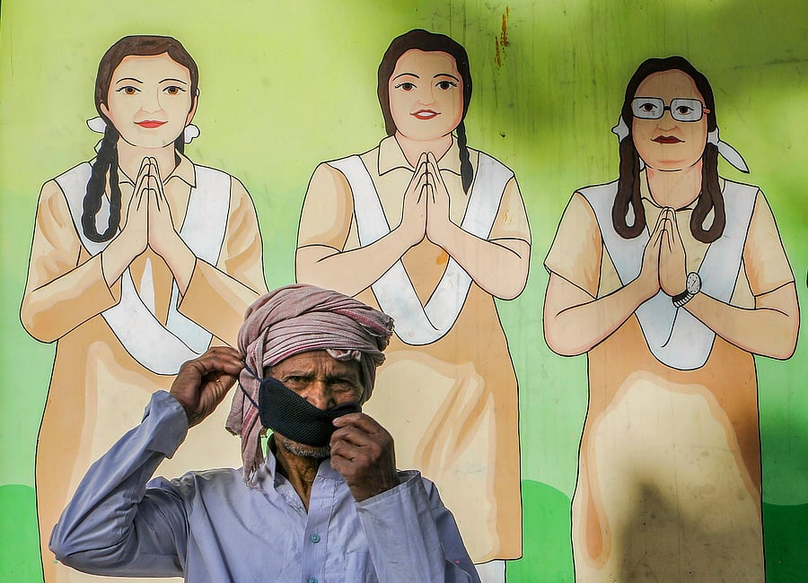 A migrant wearing a face mask waits for buses at Vinod Nagar to leave for his native place, during the fourth phase of the COVID-19. (PTI Photo)