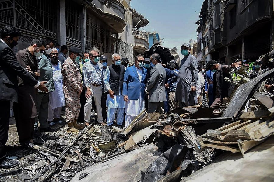Pakistan's Aviation Minister Ghulam Sarwar Awana (C-L in black jacket) visits along with Governor of Province Sindh, Imran Ismail (C-R in blue jacket), at the site a day after a Pakistan International Airlines aircraft crashed in a residential area in Karachi. (AFP Photo)