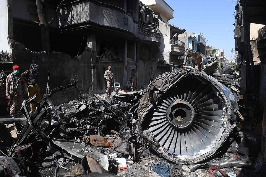Security personnel stand beside the wreckage of a plane at the site after a Pakistan International Airlines aircraft crashed in a residential area days before, in Karachi on May 24, 2020. - Ninety-seven people were killed and two survived when a passenger plane crashed into homes in Pakistan's southern city of Karachi on May 22. (Photo by AFP)