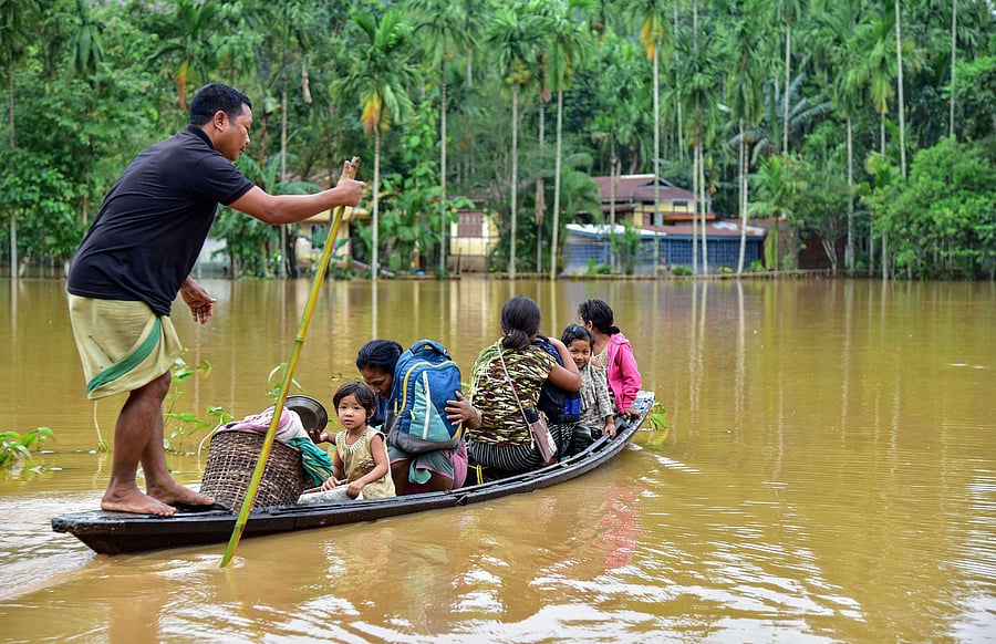 Villagers use a country boat to shift from a flooded locality following heavy rainfall at Bolbola in Goalapra district of Assam. (PTI photo)