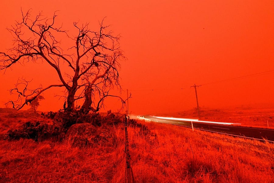 A long exposure picture shows a car commuting on a road as the sky turns red from smoke of the Snowy Valley bushfire on the outskirts of Cooma. AFP/File