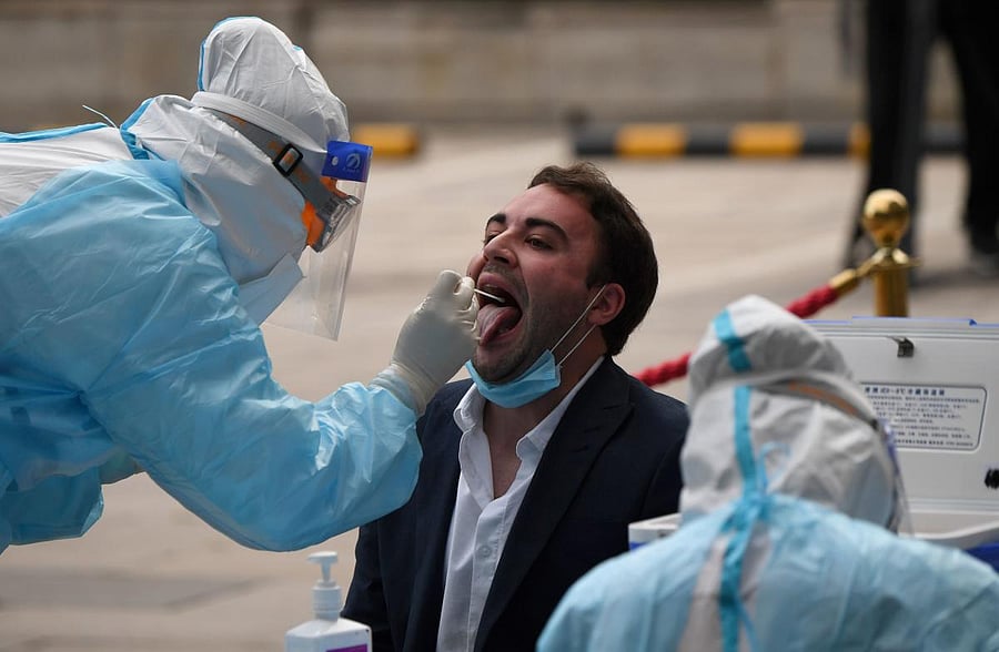 A medical worker wearing full protective gear takes a swab sample from a journalist to be tested for the COVID-19 coronavirus. AFP