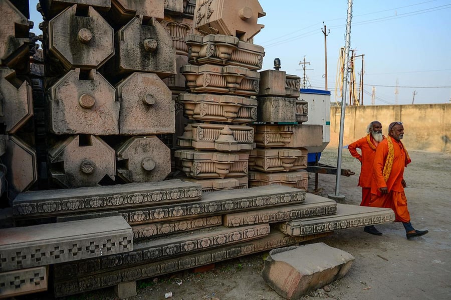 In this picture taken on November 12, 2019, Hindu devotees walk past stone slabs earmarked for the construction of a Hindu God Ram temple Ram Janmabhoomi Nyas workshop in Ayodhya, after the Supreme Court verdict on the disputed religious site. Credit: AFP Photo