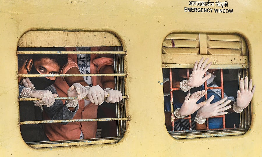 Migrants waves through windows after arriving by a special train from Mumbai at Howrah station, during the ongoing nationwide COVID-19 lockdown, in Kolkata. (PTI Photo)