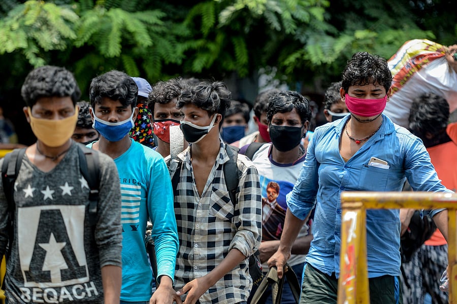 Migrant workers and families gather in front of a police station to get transferred to a railway station to board a special train to Bihar state after the government eased a nationwide lockdown. (AFP Photo)
