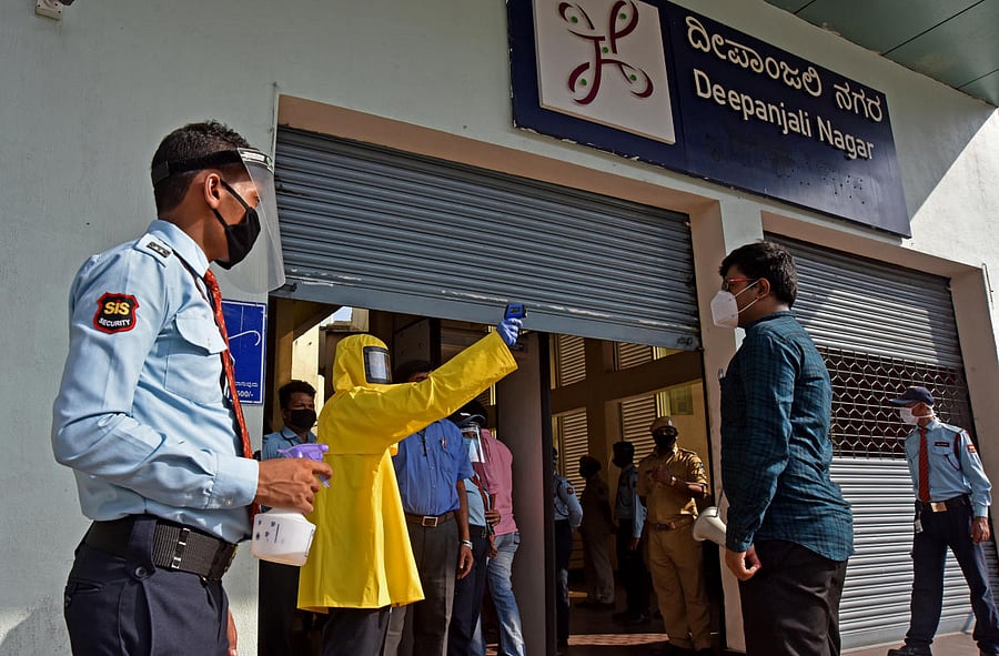 A commuter shows the Aarogya Setu app on her phone to a guard at the Deepanjali Nagar metro station on Friday. (R) A worker checks the temperature of a passenger. DH PHOTOS/M S MANJUNATH