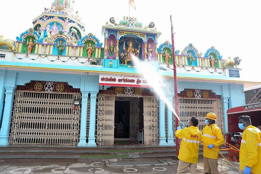 The personnel of Fire and Emergency Services disinfect a temple in Davangere on Sunday. Temples across the state will reopen on Monday after a gap of two months.  DH Photo/Satish Badiger